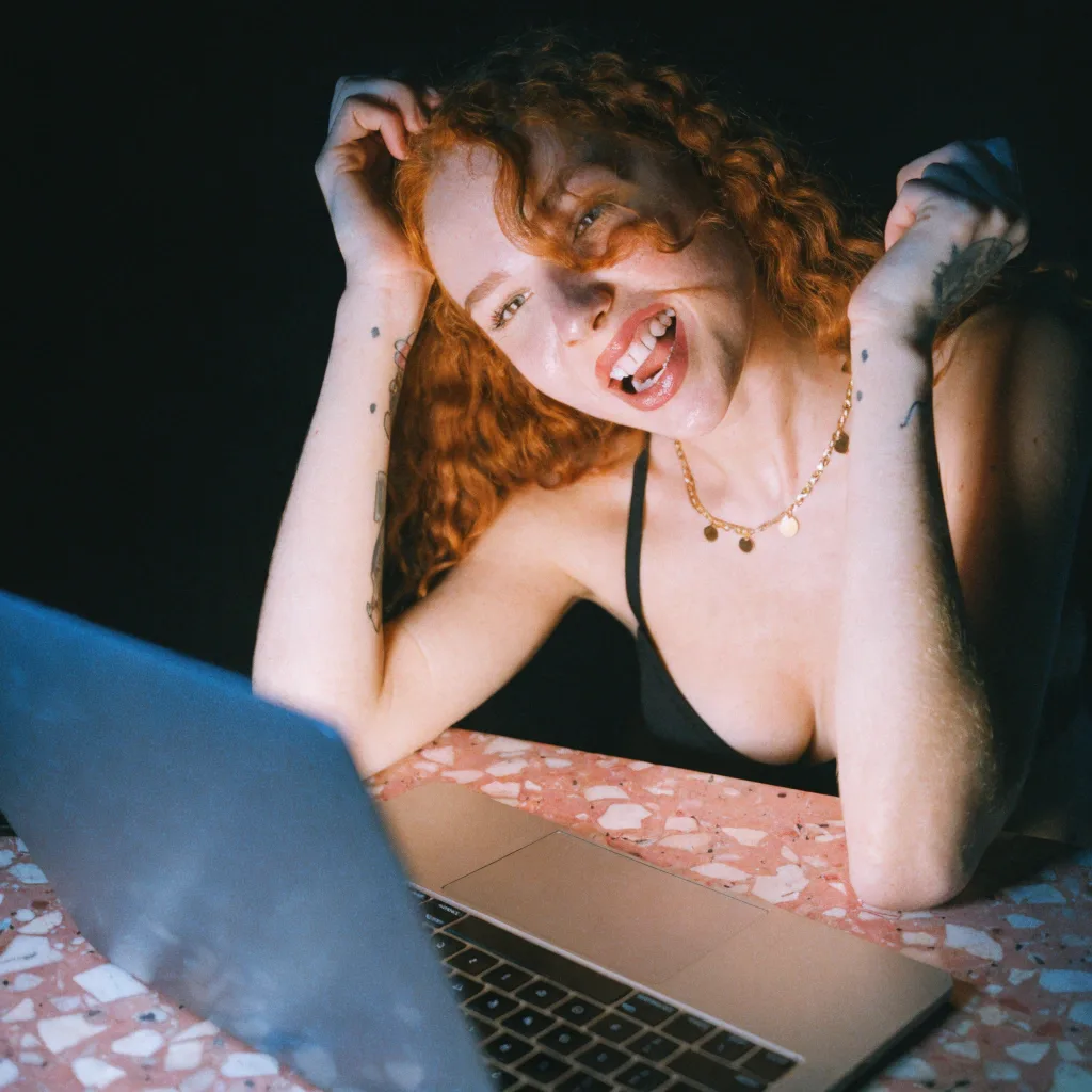 red-haired woman laughing at her laptop