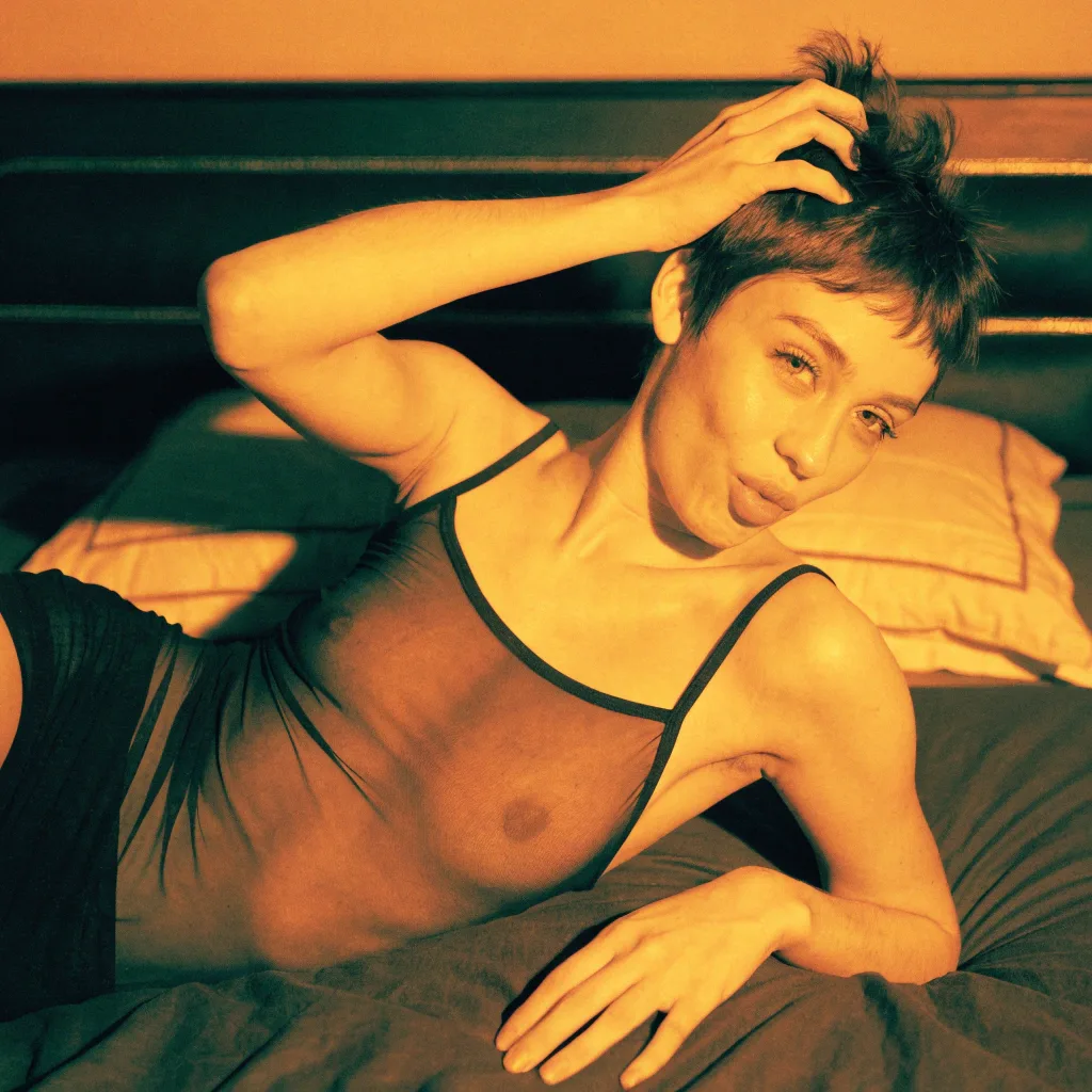 short-haired woman lying on a bed in amber light